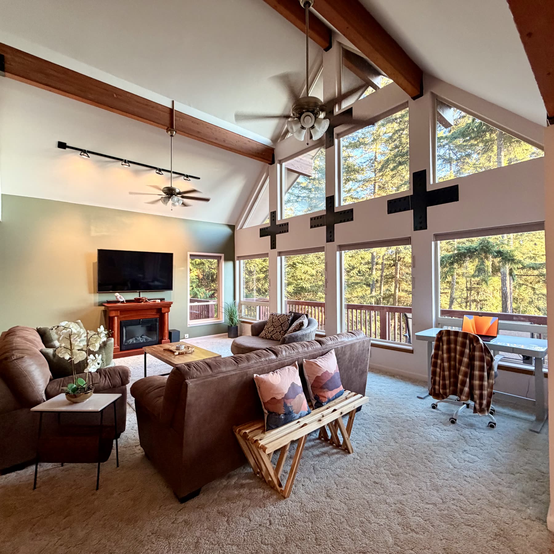 Living room seating and wall of windows facing the forest